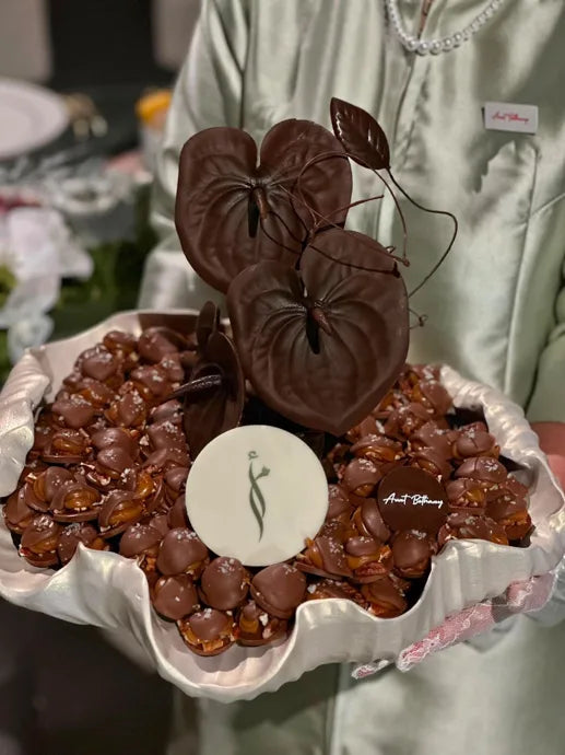 A service attendant holding a tray of chocolates with sculpted chocolate leaves